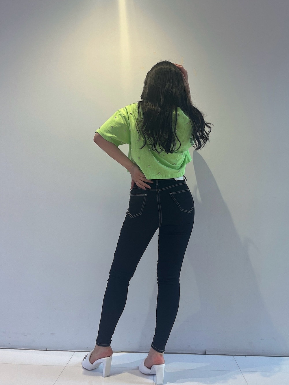 グリーン系のTシャツ/カットソー、ブラック系のデニムパンツ、ホワイト系のサンダルを着用したレディースの春コーディネートの3枚目の写真