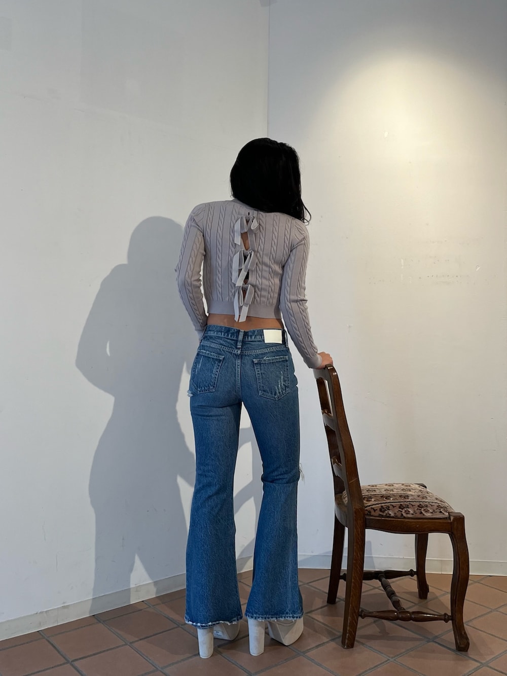 グレー系のニット/セーター、ブルー系のデニムパンツ、ホワイト系のブーツを着用したレディースの秋コーディネートの2枚目の写真