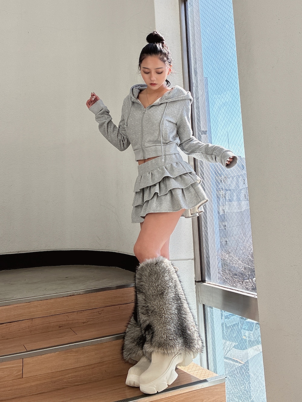 グレー系のパーカー、グレー系のスカート、ホワイト系のブーツを着用したレディースの冬コーディネートの2枚目の写真