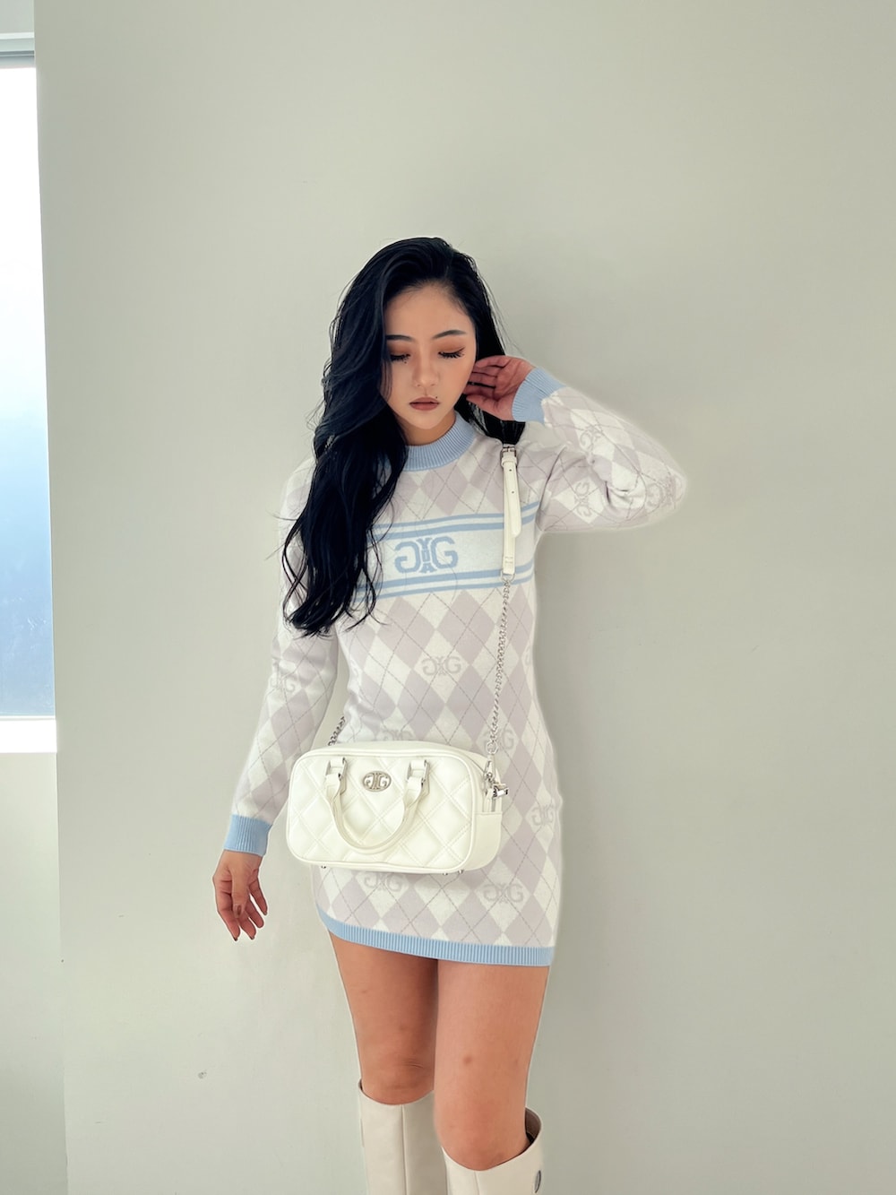 ブルー系のワンピース、ホワイト系のハンドバッグ、ホワイト系のブーツを着用したレディースの冬コーディネートの3枚目の写真