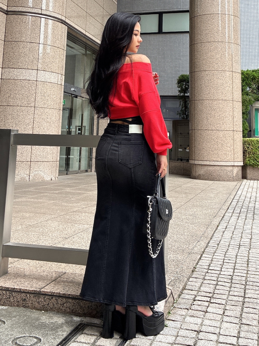 レッド系のTシャツ/カットソー、ブラック系のデニムスカート、ブラック系のハンドバッグを着用したレディースの秋コーディネートの4枚目の写真