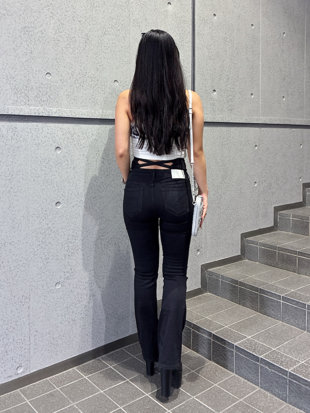 ホワイト系のチューブトップ、ブラック系のデニムパンツ、ブラック系のブーツを着用したレディースの夏コーディネートの3枚目の写真