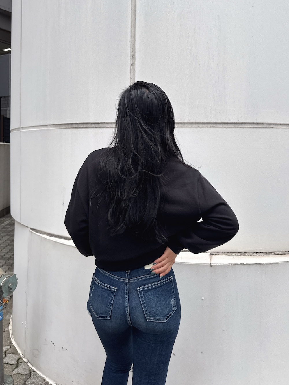 ブラック系のスウェット、ブルー系のデニムパンツ、ブルー系のパンプスを着用したレディースの冬コーディネートの3枚目の写真