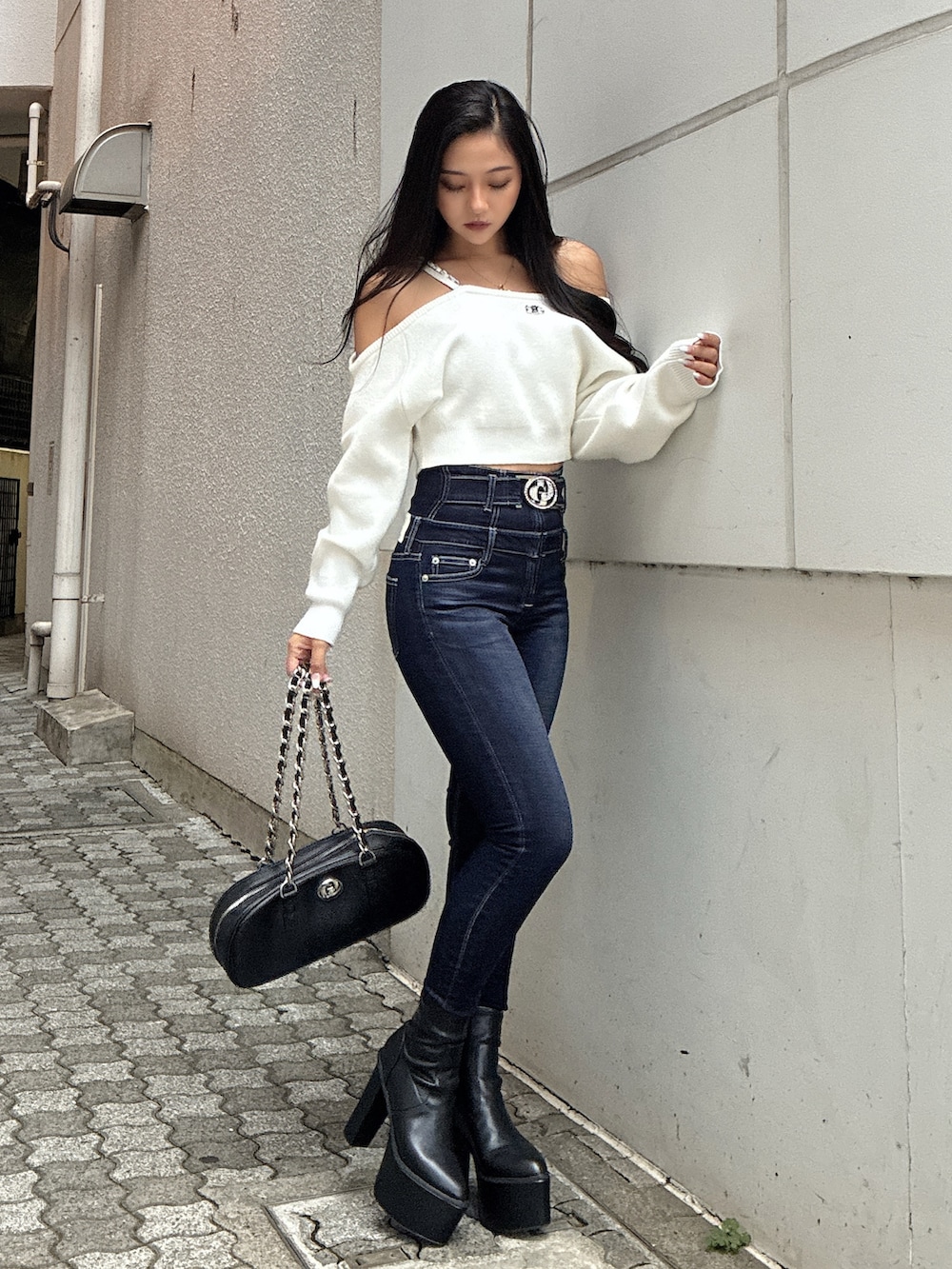 ホワイト系のニット/セーター、ブルー系のデニムパンツ、ブラック系のブーツを着用したレディースの秋コーディネートの2枚目の写真