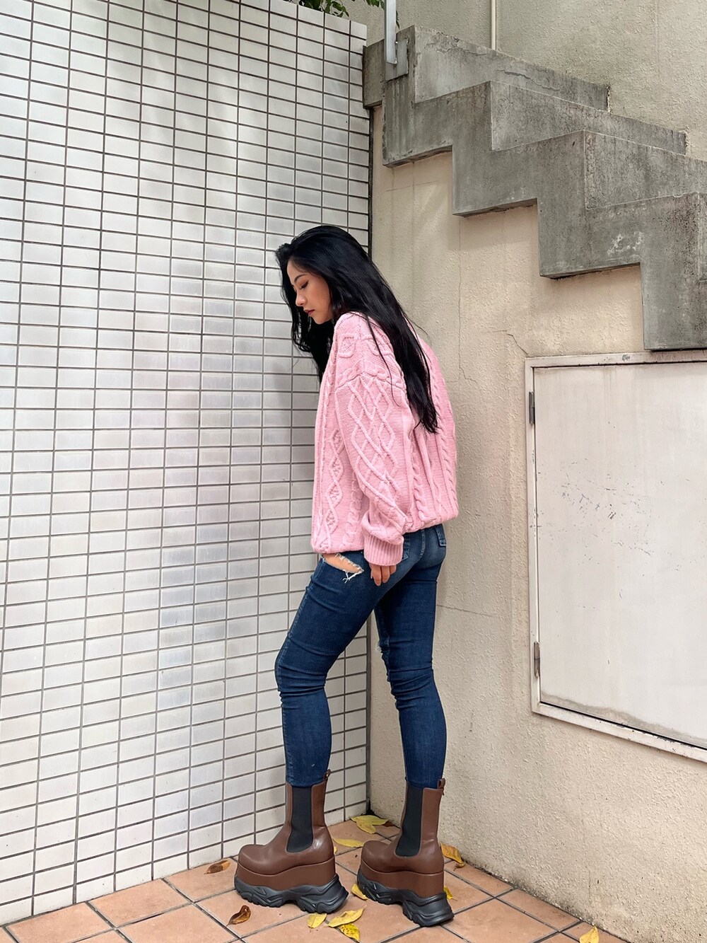 ピンク系のニット/セーター、ブルー系のデニムパンツ、ブラウン系のブーツを着用したレディースの秋コーディネートの2枚目の写真