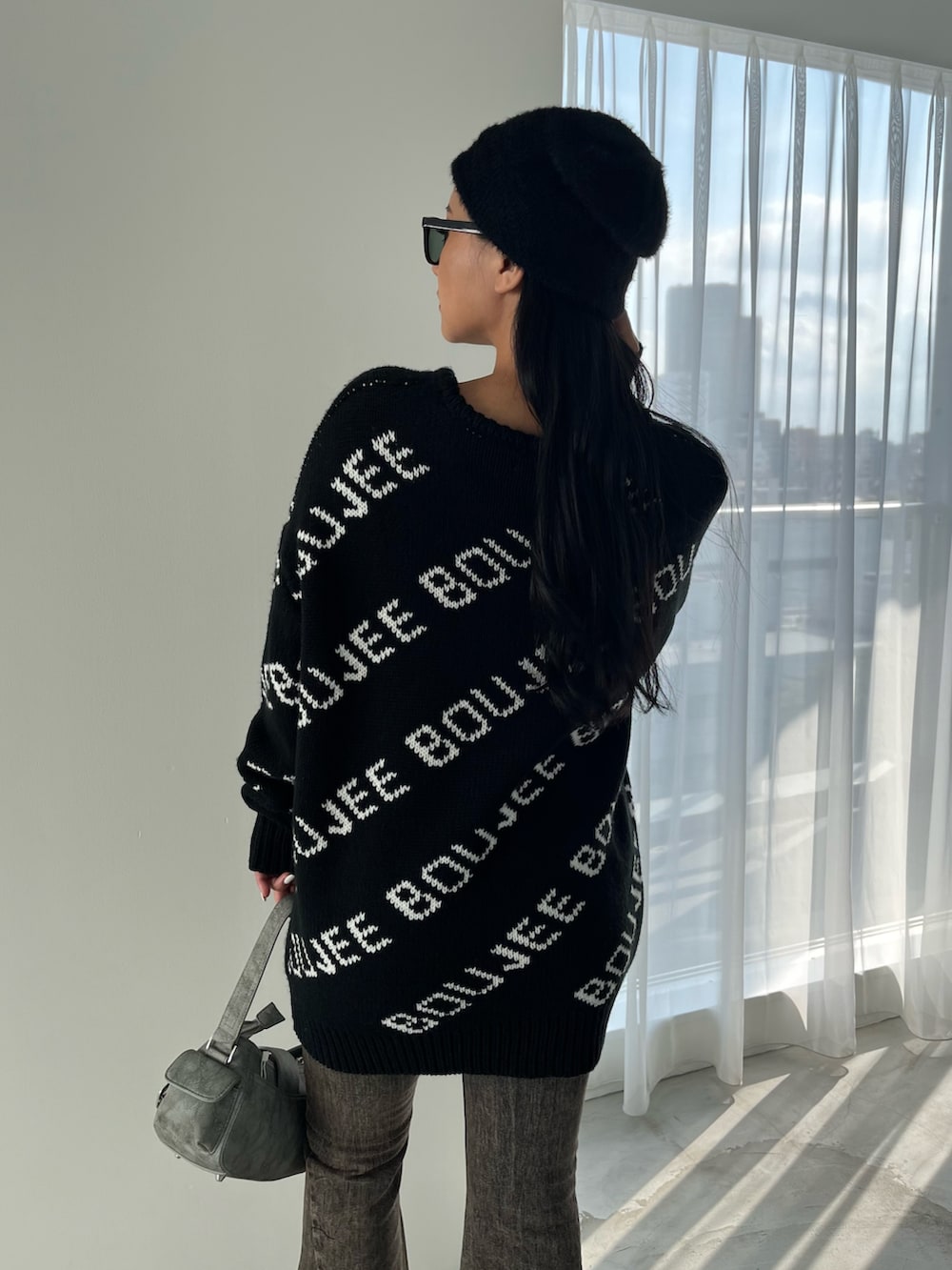 グリーン系のショルダーバッグ、ブラック系のブーツ、ブラック系のデニムパンツを着用したレディースの秋コーディネートの3枚目の写真