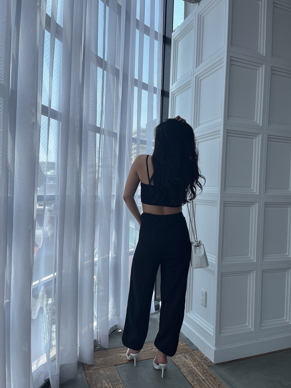 ブラック系のキャミソール、ブラック系のスウェットパンツ、ホワイト系のパンプスを着用したレディースの夏コーディネートの2枚目の写真