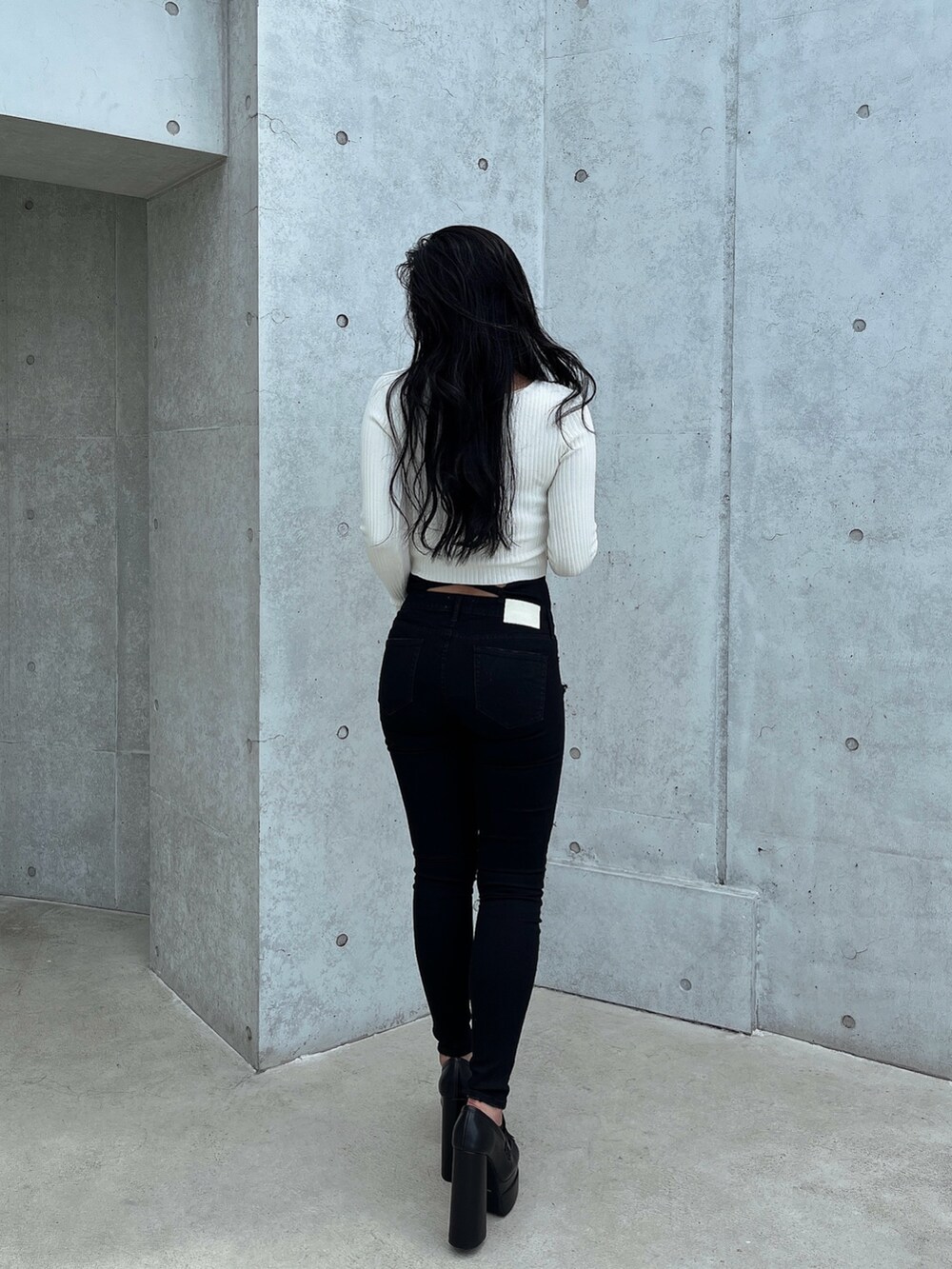 ホワイト系のニット/セーター、ブラック系のデニムパンツ、ブラック系のパンプスを着用したレディースの秋コーディネートの2枚目の写真