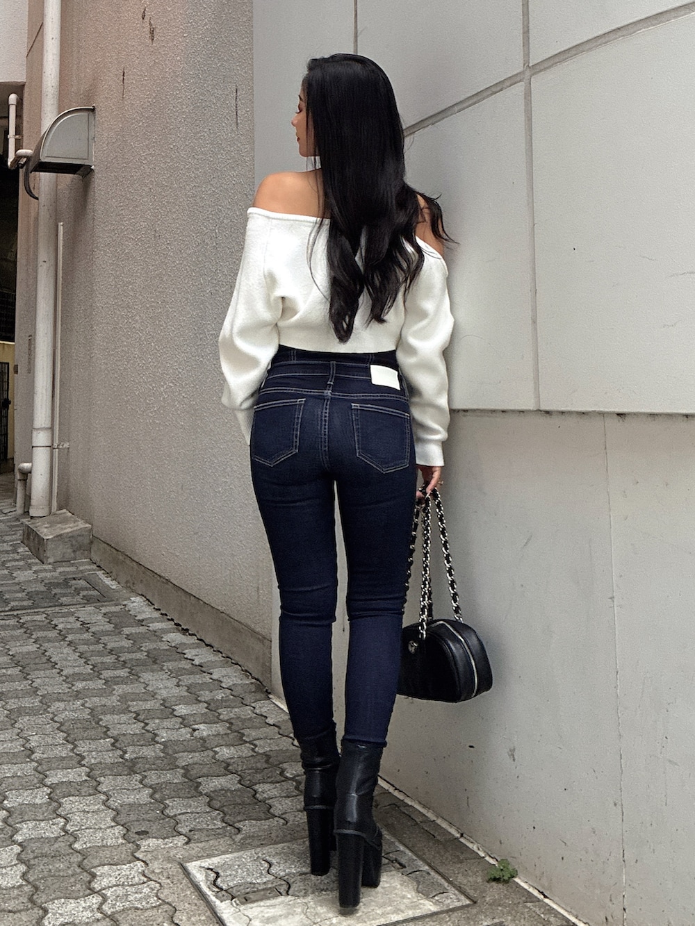 ホワイト系のニット/セーター、ブルー系のデニムパンツ、ブラック系のブーツを着用したレディースの秋コーディネートの3枚目の写真