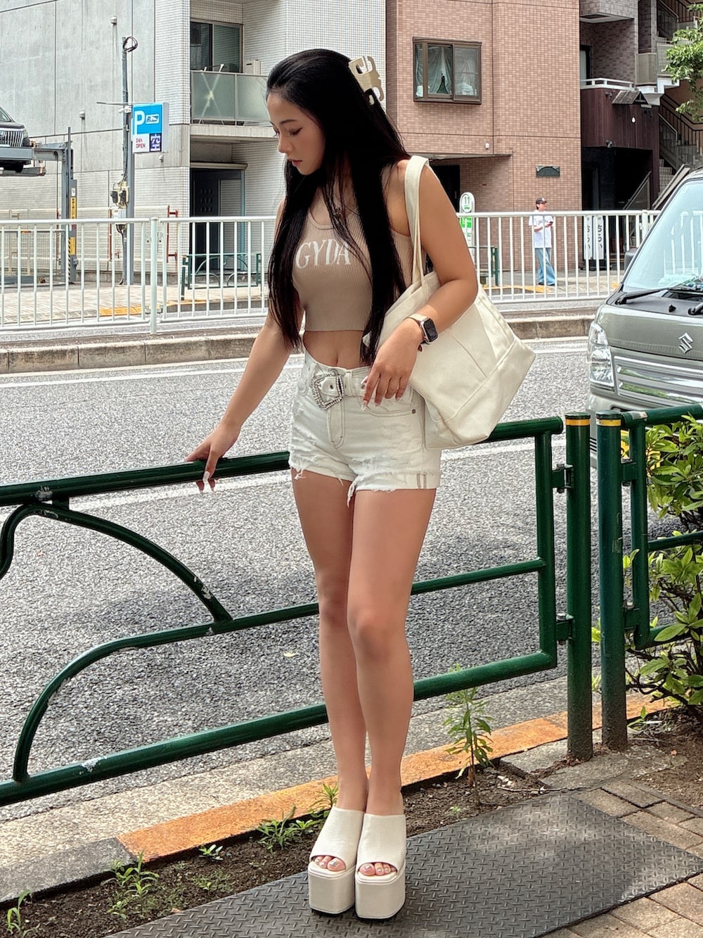 ベージュ系のキャミソール、ホワイト系のデニムパンツ、ホワイト系のサンダルを着用したレディースの夏コーディネートの2枚目の写真