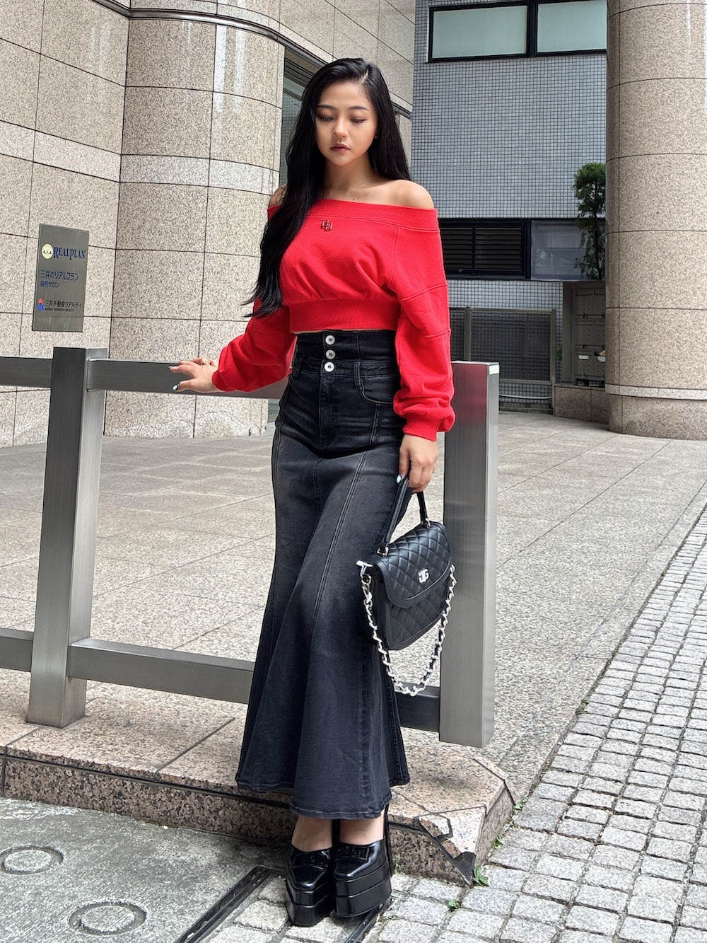 レッド系のTシャツ/カットソー、ブラック系のデニムスカート、ブラック系のハンドバッグを着用したレディースの秋コーディネートの3枚目の写真