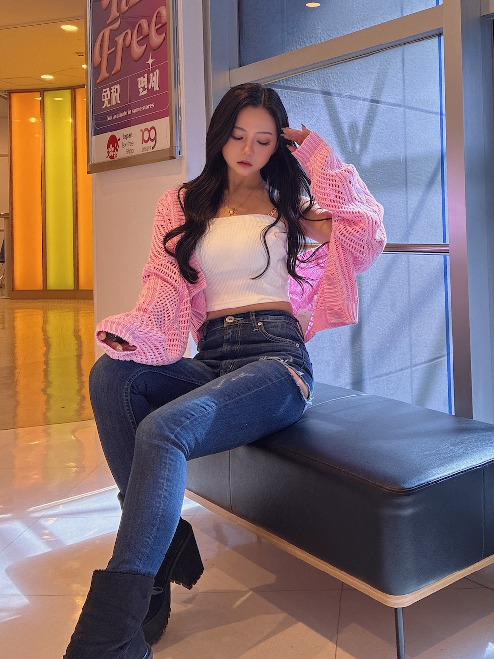 ホワイト系のチューブトップ、ピンク系のニット/セーター、ブルー系のデニムパンツを着用したレディースの春コーディネートの3枚目の写真