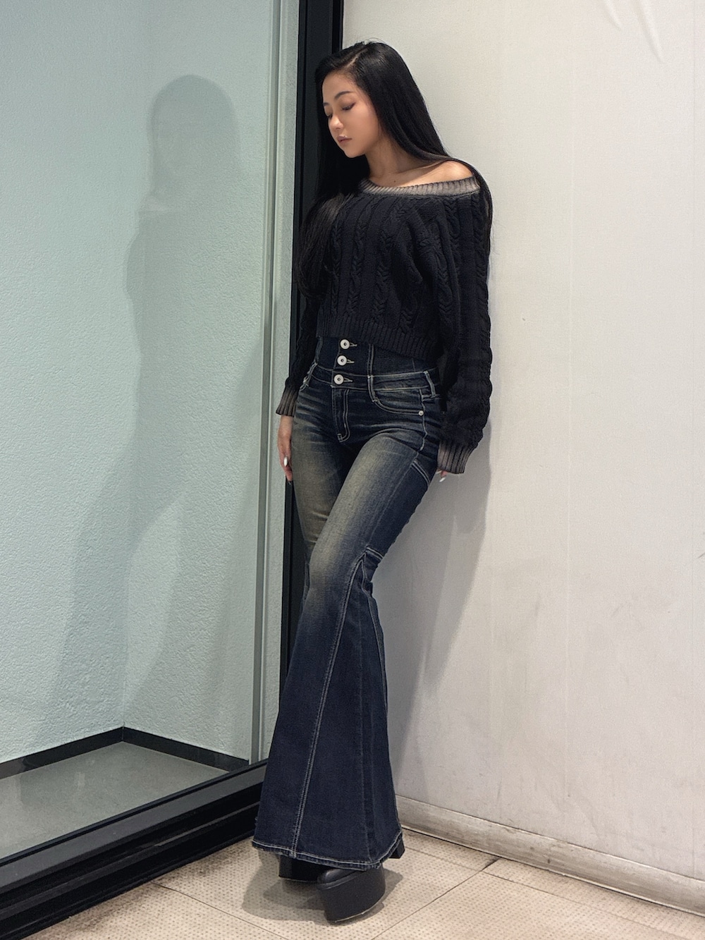 ブラック系のニット/セーター、ブルー系のデニムパンツ、ブラック系のブーツを着用したレディースの秋コーディネートの2枚目の写真