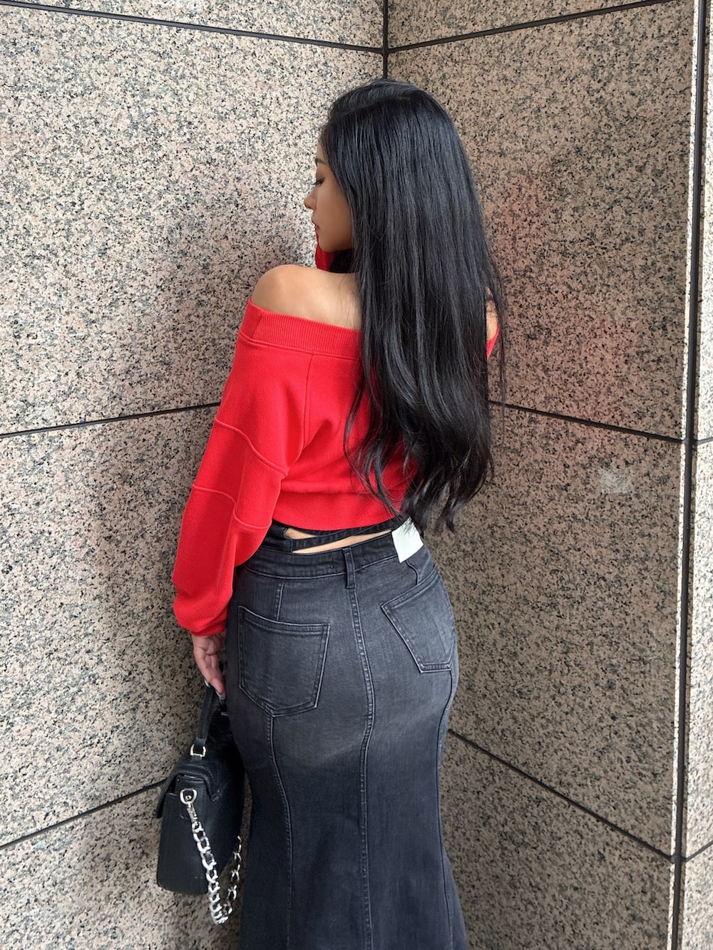 レッド系のTシャツ/カットソー、ブラック系のデニムスカート、ブラック系のハンドバッグを着用したレディースの秋コーディネートの2枚目の写真