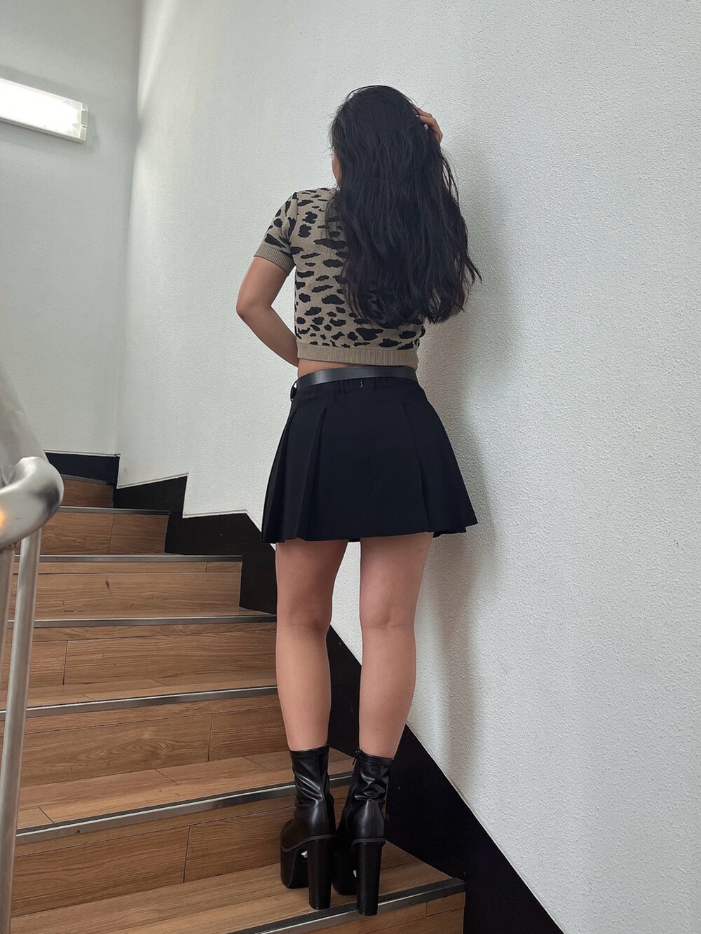 ベージュ系のニット/セーター、ブラック系のスカート、ブラック系のブーツを着用したレディースの夏コーディネートの2枚目の写真