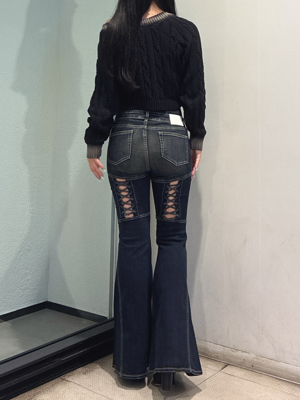 ブラック系のニット/セーター、ブルー系のデニムパンツ、ブラック系のブーツを着用したレディースの秋コーディネートの4枚目の写真