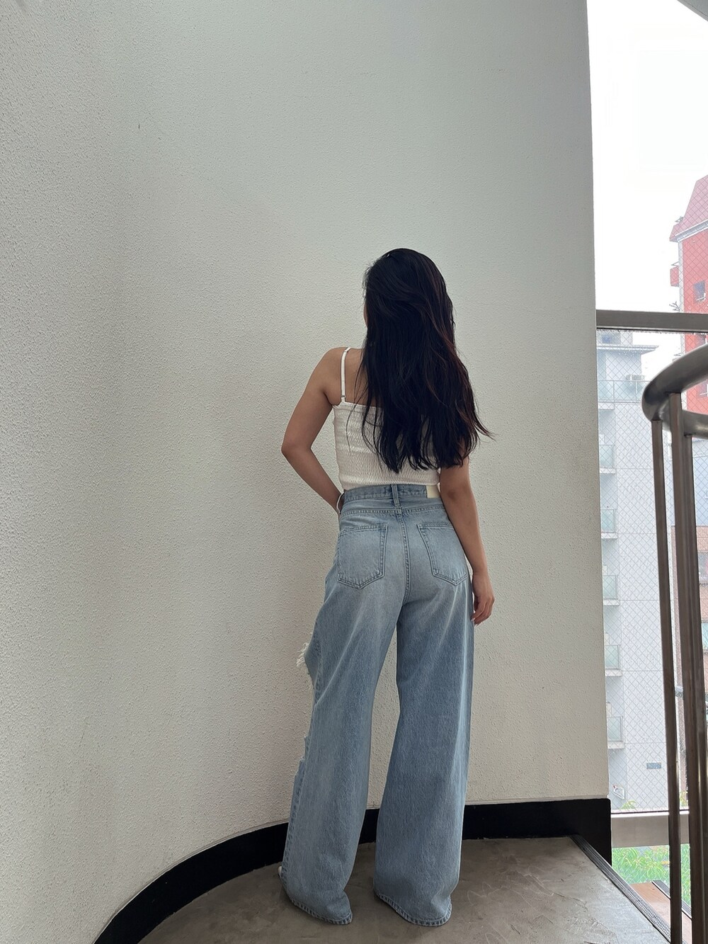 ブルー系のデニムパンツ、ホワイト系のパンプス、ホワイト系のシャツ/ブラウスを着用したレディースの夏コーディネートの2枚目の写真