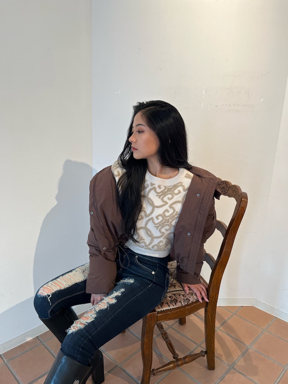 ホワイト系のニット/セーター、ブラウン系のダウンジャケット/コート、ブルー系のデニムパンツを着用したレディースの秋コーディネートの2枚目の写真