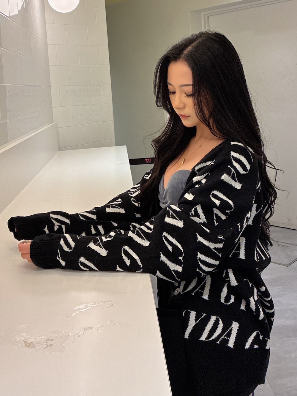 ブラック系のカーディガン/ボレロ、ブルー系のキャミソール、ブラック系のデニムパンツを着用したレディースの春コーディネートの2枚目の写真