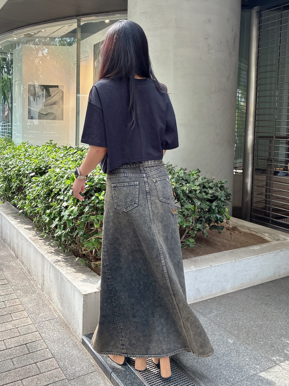 ブラック系のTシャツ/カットソー、ブルー系のデニムスカート、ブラック系のサンダルを着用したレディースの夏コーディネートの3枚目の写真