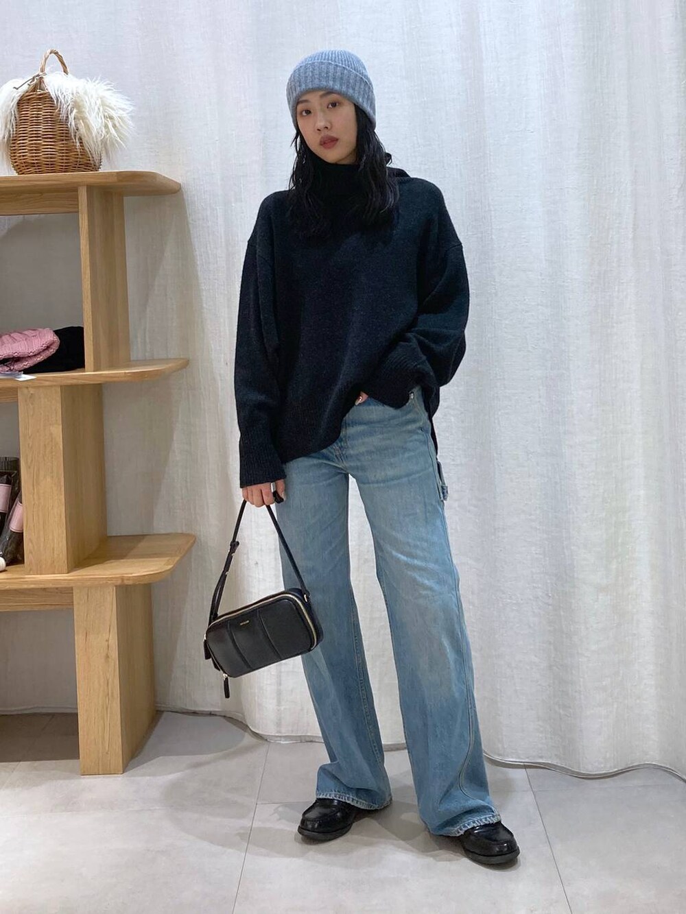 グレー系のニット/セーター、ブルー系のデニムパンツ、グレー系のニットキャップ/ビーニーを着用したレディースの冬コーディネートの2枚目の写真