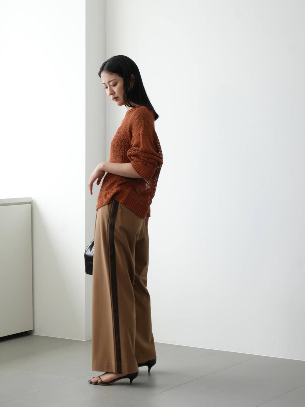 イエロー系のニット/セーター、ブラウン系のサンダル、ベージュ系のその他パンツを着用したレディースの夏コーディネートの2枚目の写真