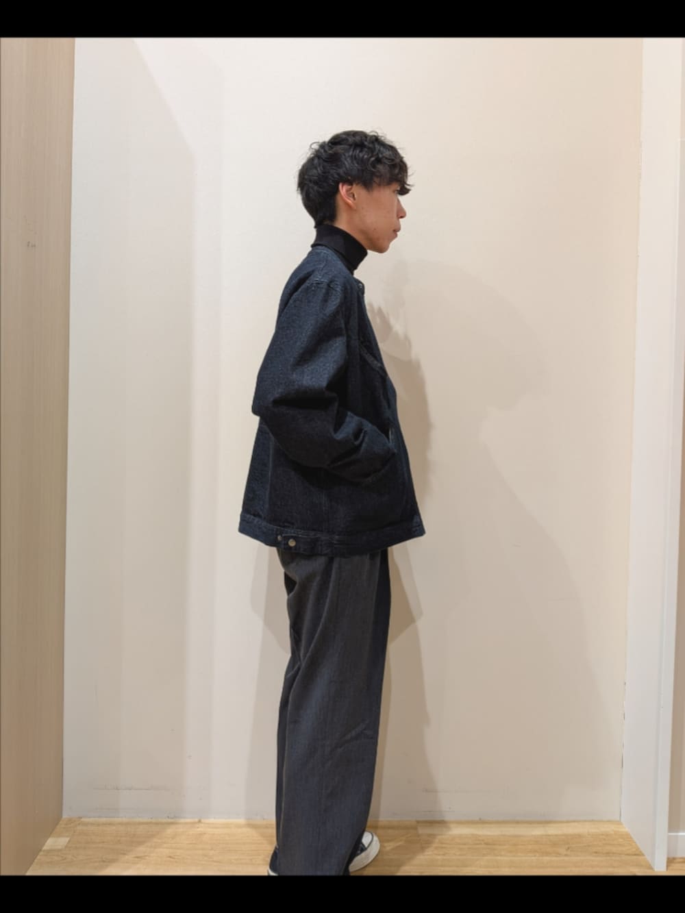 ブルー系のデニムジャケット、ブラック系のニット/セーター、グレー系のその他パンツを着用したメンズの秋コーディネートの4枚目の写真