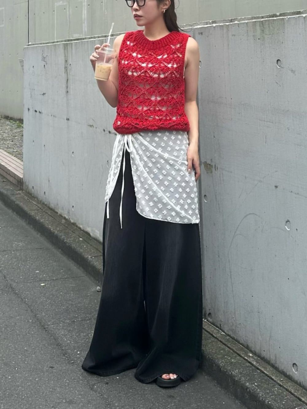 ブラック系のデニムパンツ、レッド系のニット/セーター、ブラック系のサンダルを着用したレディースの夏コーディネートの3枚目の写真