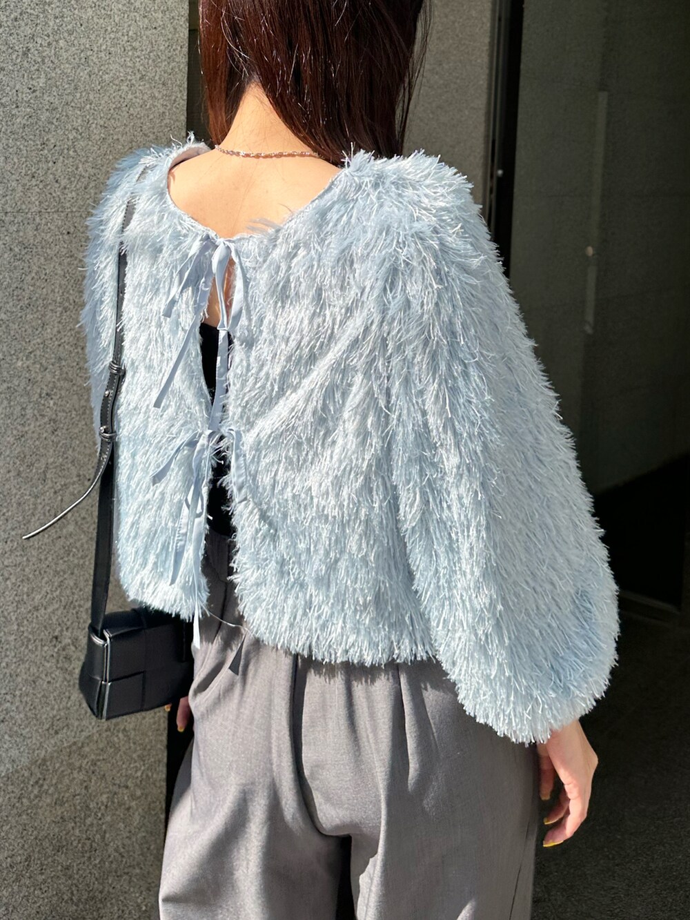 グレー系のスラックス、ブルー系のニット/セーター、ブラック系のバッグを着用したレディースの春コーディネートの2枚目の写真