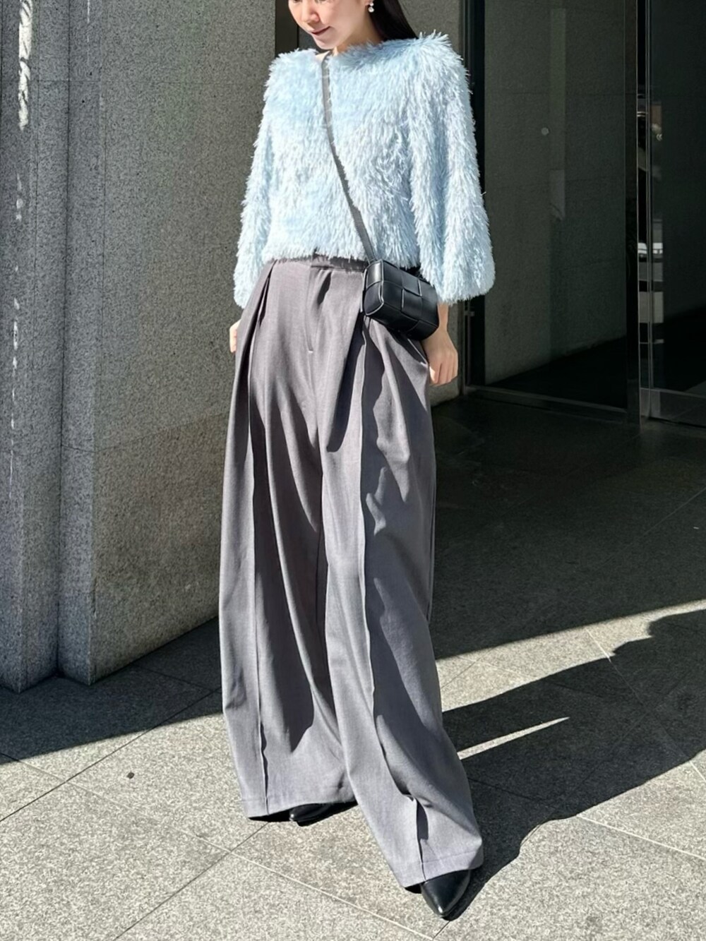 グレー系のスラックス、ブルー系のニット/セーター、ブラック系のバッグを着用したレディースの春コーディネートの3枚目の写真