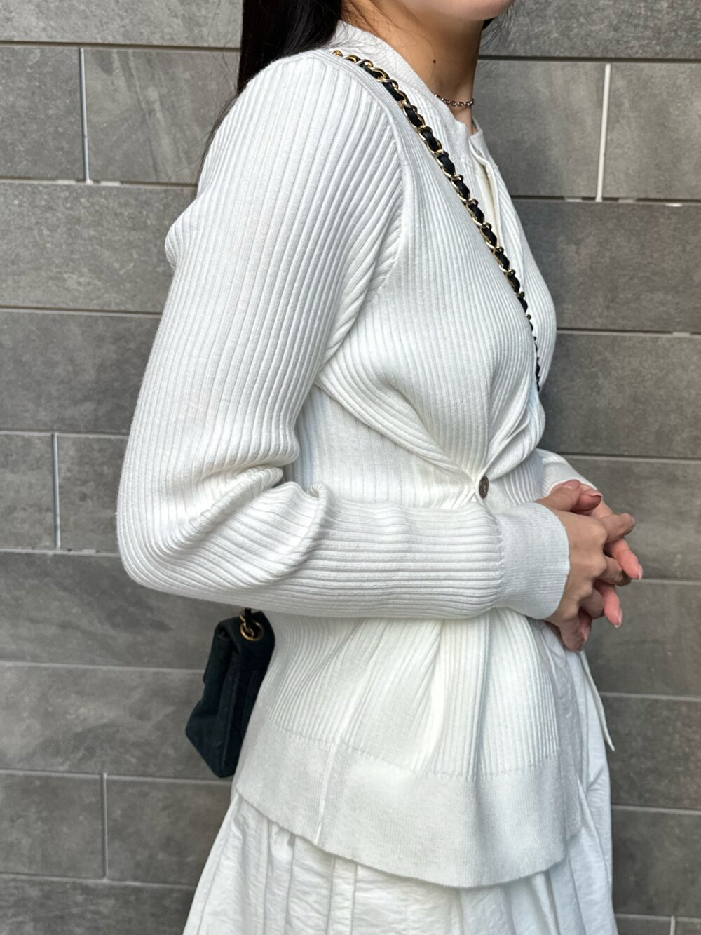 ホワイト系のスカート、ホワイト系のニット/セーター、ブラック系のバッグを着用したレディースの春コーディネートの3枚目の写真