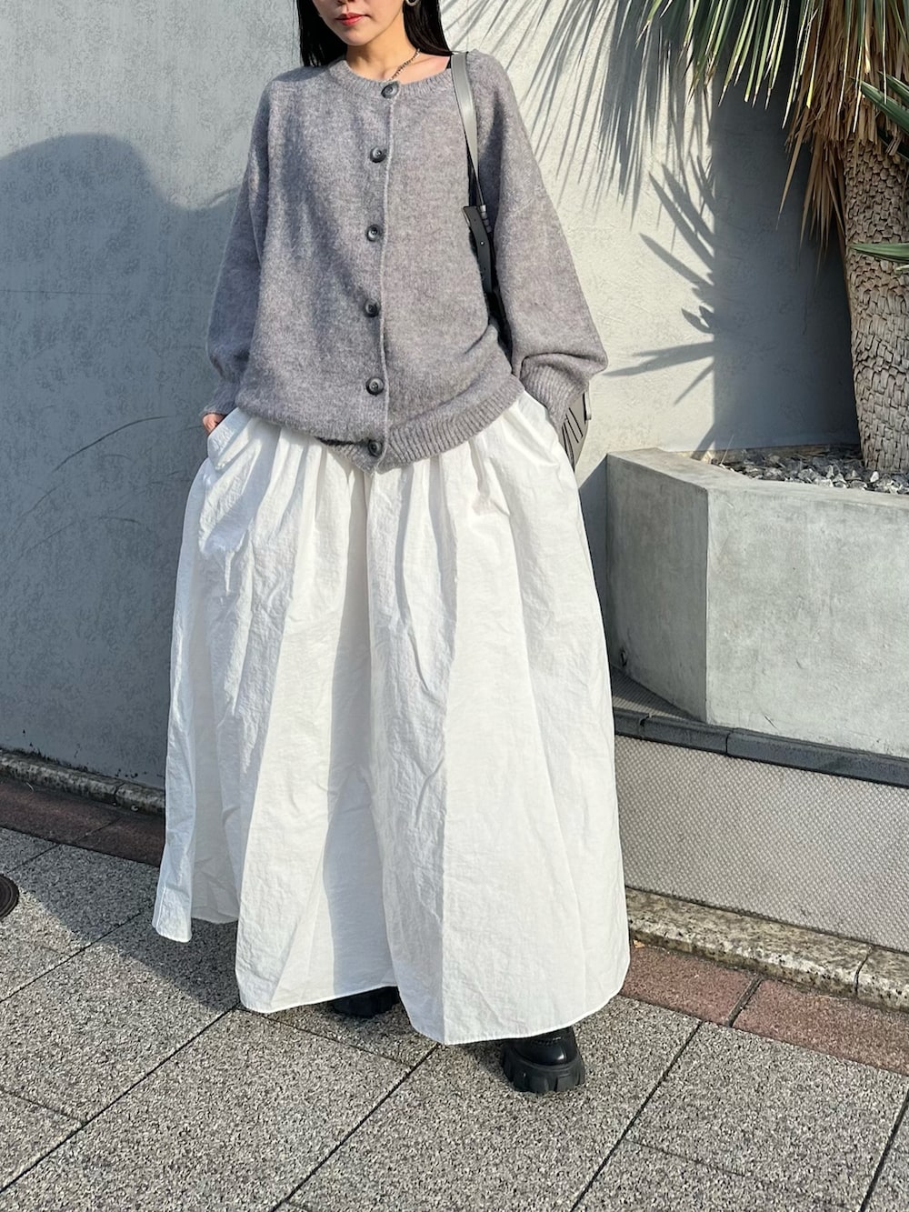 ホワイト系のスカート、グレー系のカーディガン/ボレロ、グレー系のトートバッグを着用したレディースの冬コーディネートの2枚目の写真