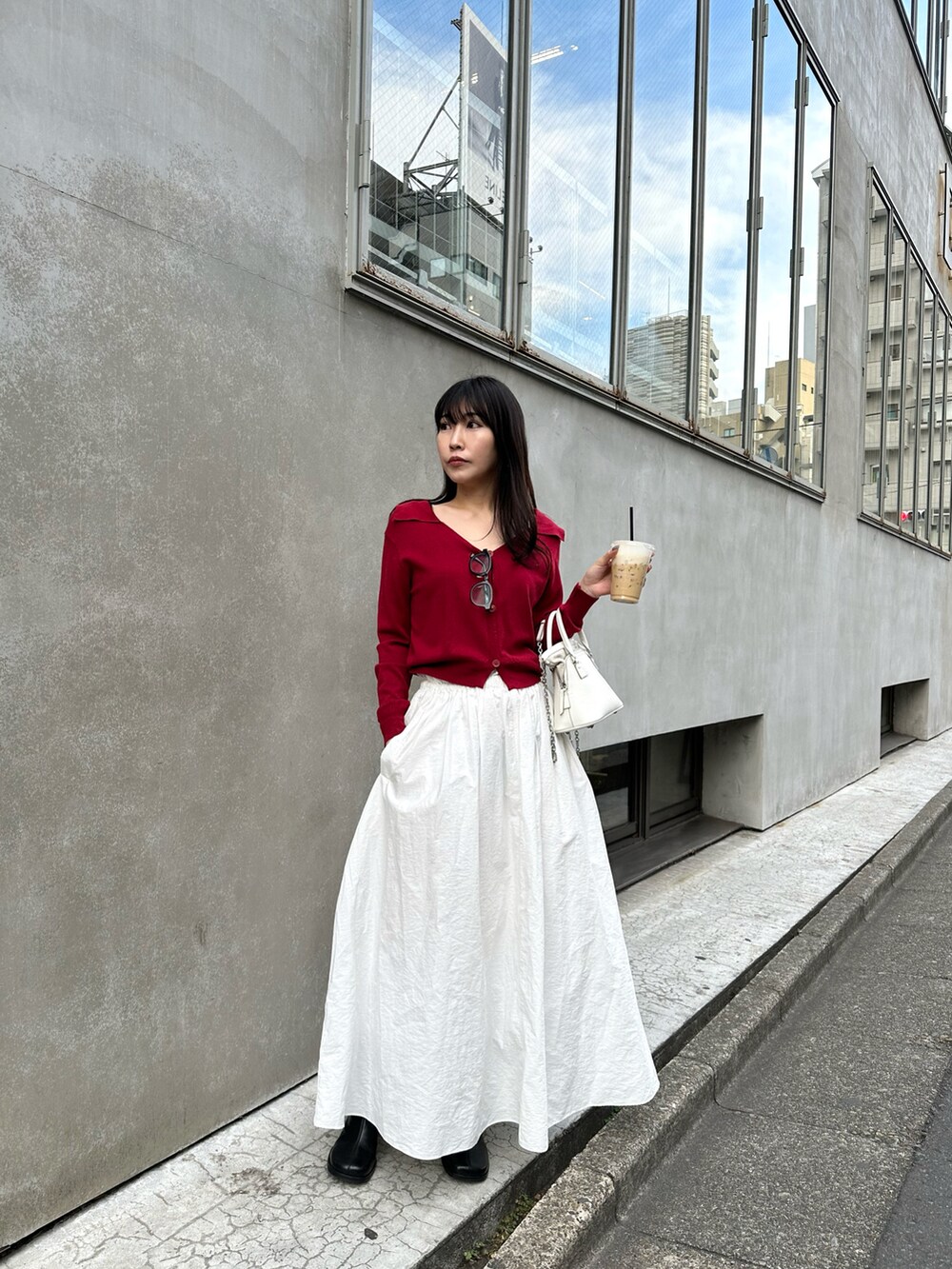 ホワイト系のショルダーバッグ、ホワイト系のスカート、レッド系のカーディガン/ボレロを着用したレディースの冬コーディネートの3枚目の写真