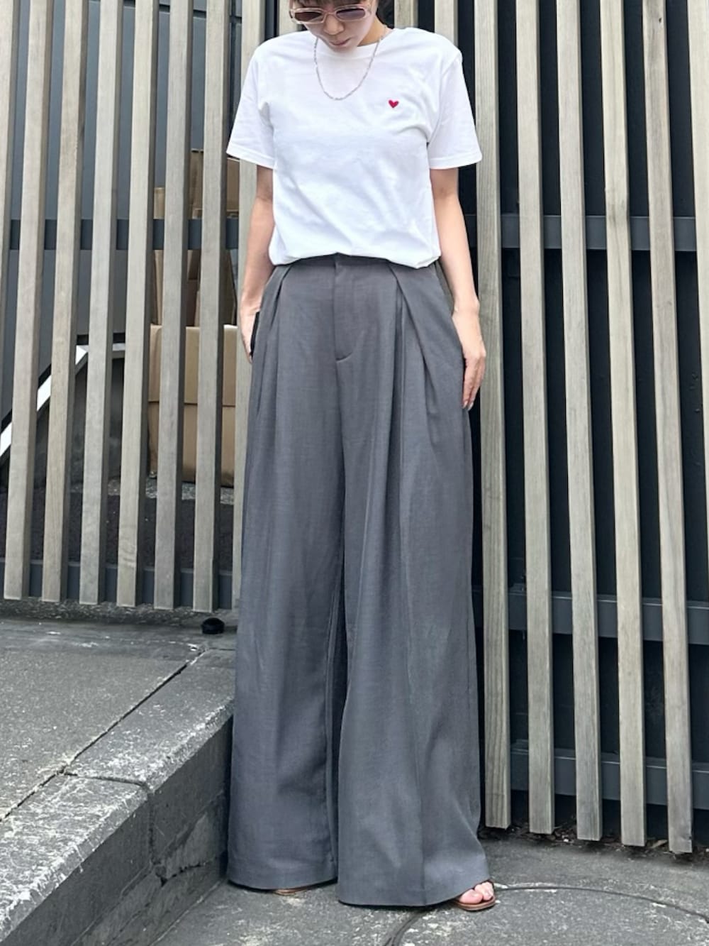 グレー系のスラックス、ブラウン系のサンダル、ホワイト系のTシャツ/カットソーを着用したレディースの春コーディネートの2枚目の写真