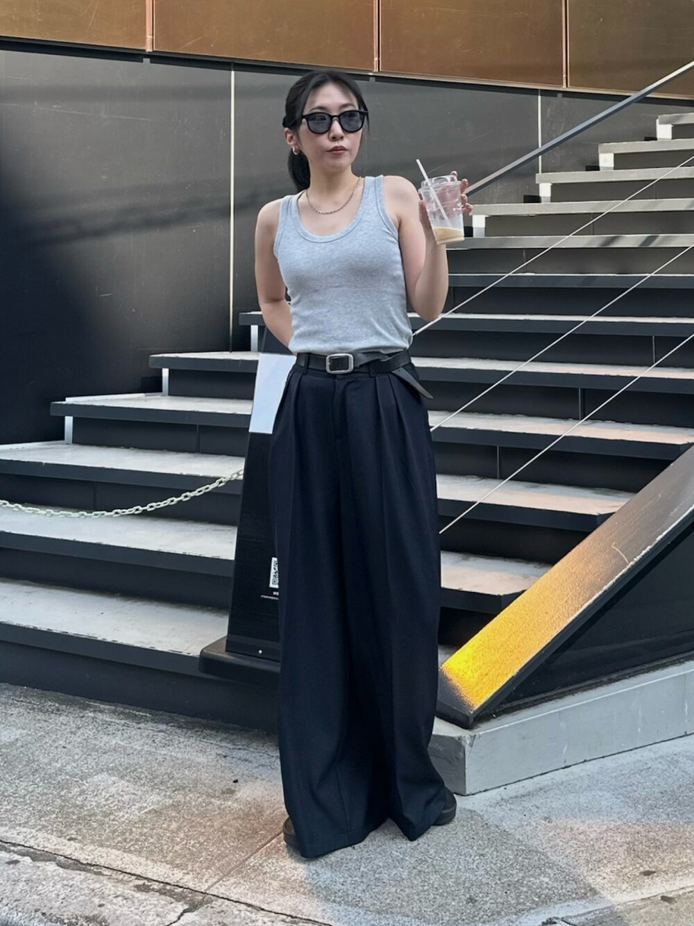 ブルー系のスラックス、ブラック系のサンダル、グレー系のタンクトップを着用したレディースの夏コーディネートの2枚目の写真