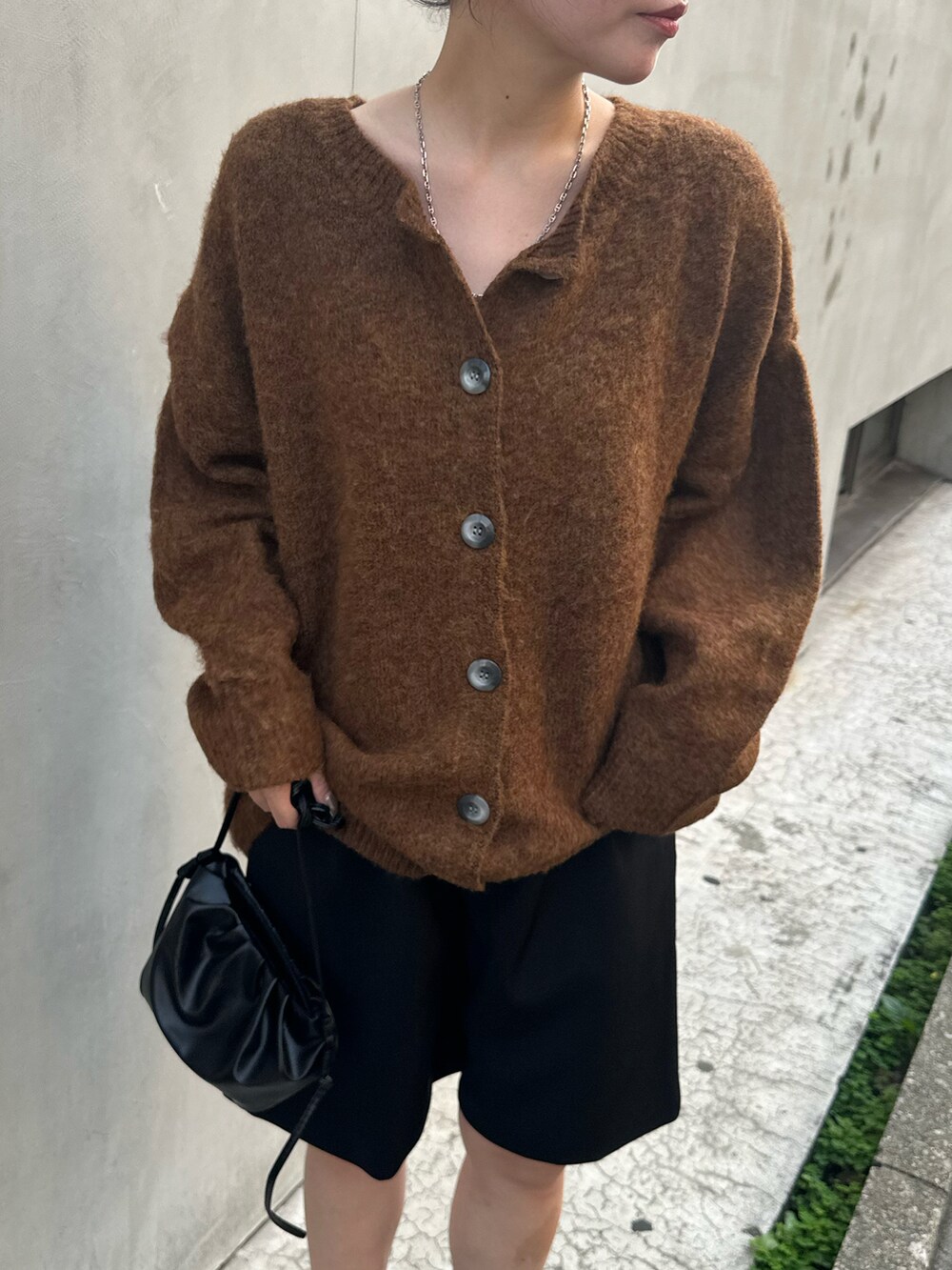 ブラウン系のカーディガン/ボレロ、ブラック系のブーツ、ブラック系のスラックスを着用したレディースの秋コーディネートの3枚目の写真