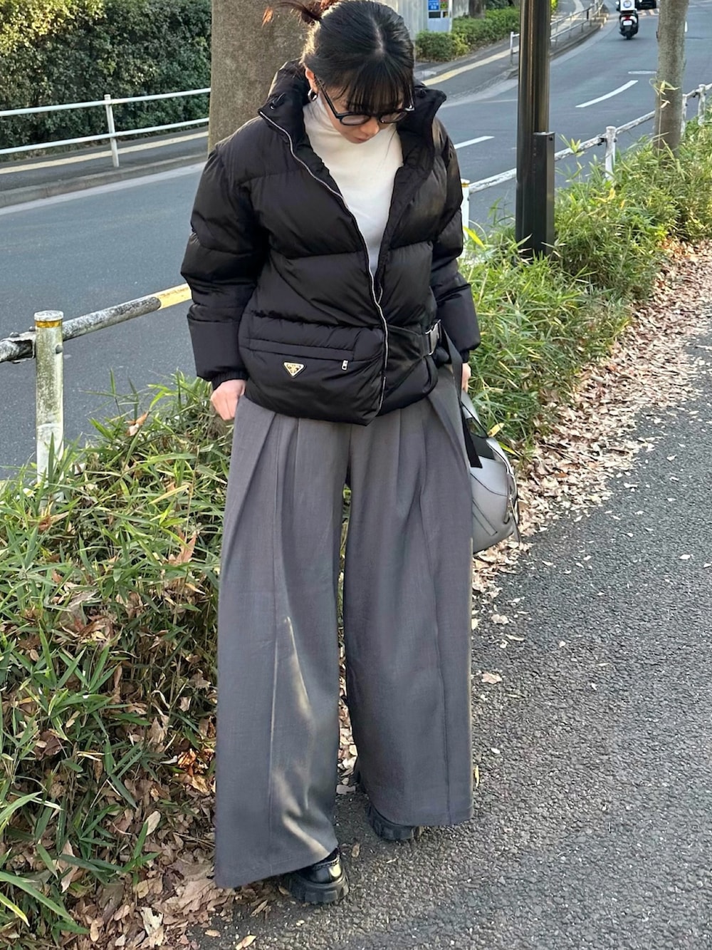 グレー系のスラックス、グレー系のトートバッグ、ホワイト系のニット/セーターを着用したレディースの冬コーディネートの2枚目の写真