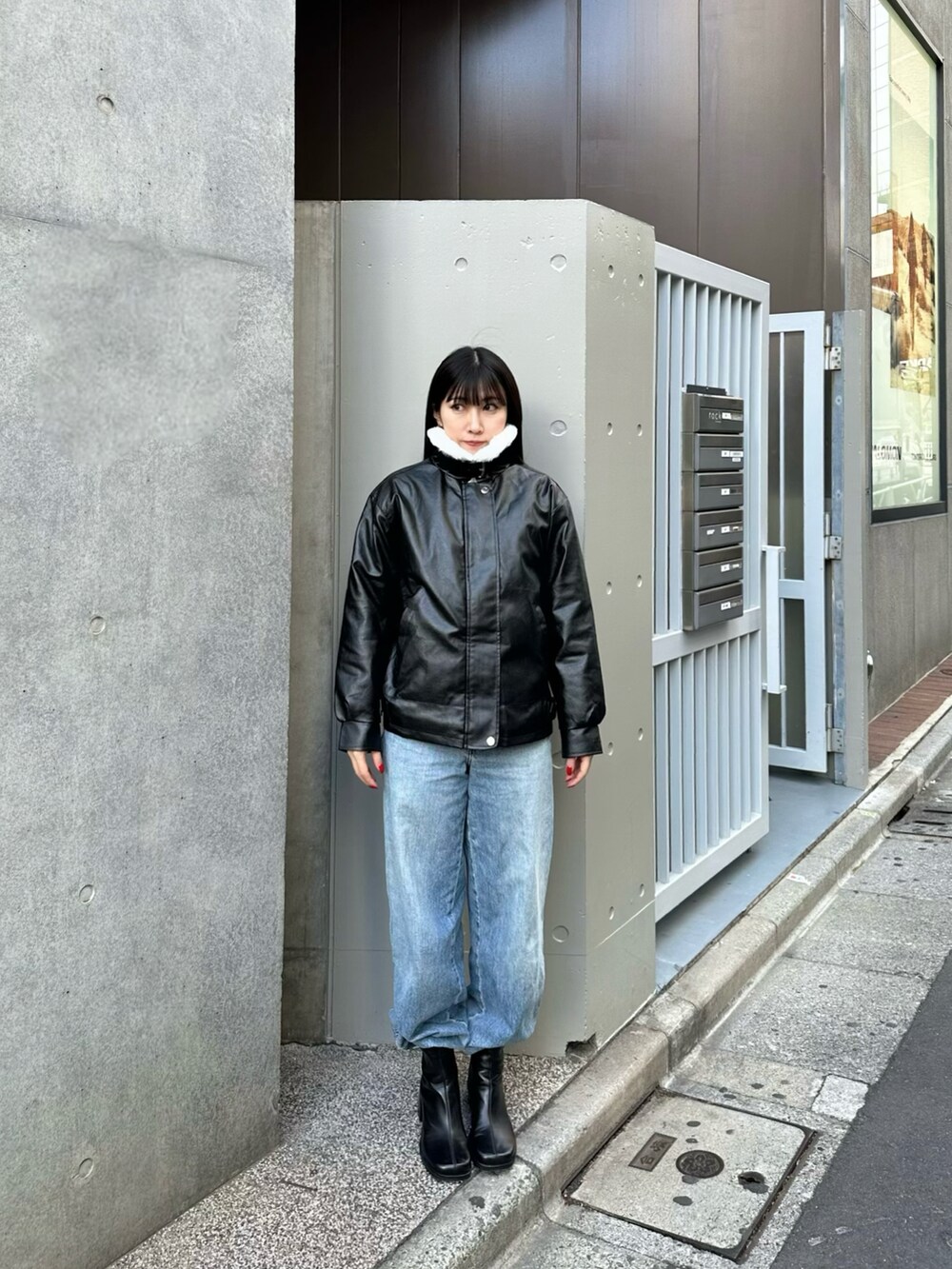 ブラック系のブーツ、ブルー系のデニムパンツ、ブラック系のムートンコートを着用したレディースの冬コーディネートの2枚目の写真