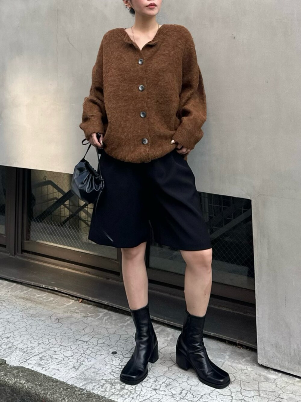 ブラウン系のカーディガン/ボレロ、ブラック系のブーツ、ブラック系のスラックスを着用したレディースの秋コーディネートの2枚目の写真