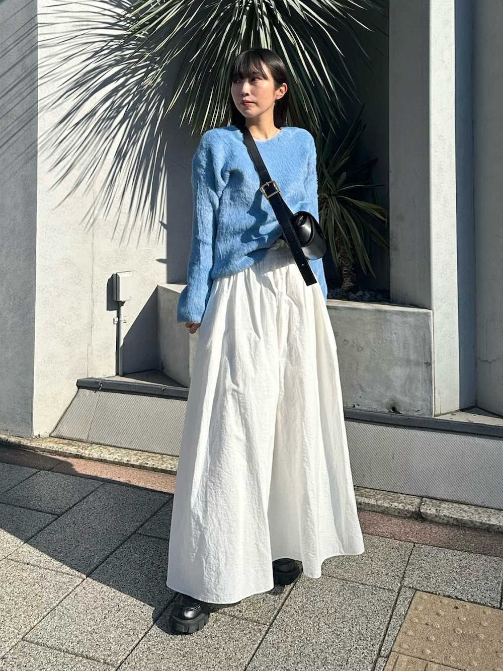 ホワイト系のスカート、ブルー系のニット/セーター、シルバー系のネックレスを着用したレディースの冬コーディネートの2枚目の写真