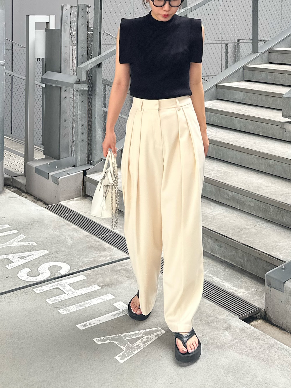 ホワイト系のその他パンツ、ブラック系のサンダル、ホワイト系のショルダーバッグを着用したレディースの夏コーディネートの2枚目の写真