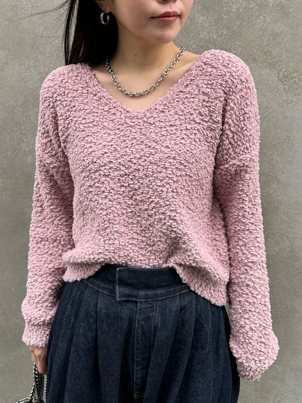 ブルー系のデニムパンツ、ブラック系のショルダーバッグ、ピンク系のニット/セーターを着用したレディースの冬コーディネートの3枚目の写真