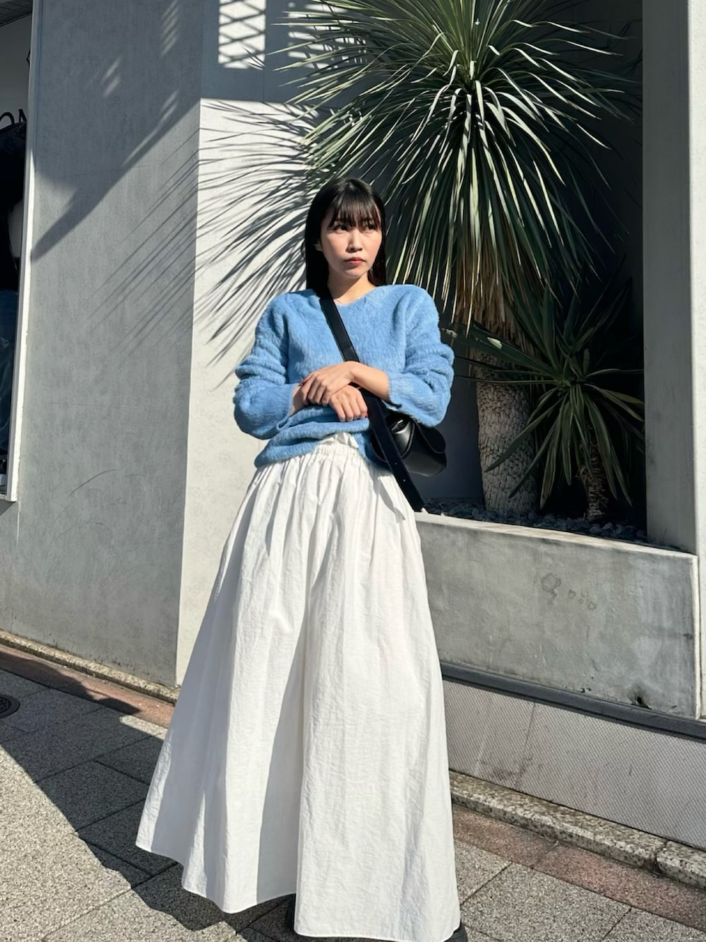 ホワイト系のスカート、ブルー系のニット/セーター、シルバー系のネックレスを着用したレディースの冬コーディネートの3枚目の写真