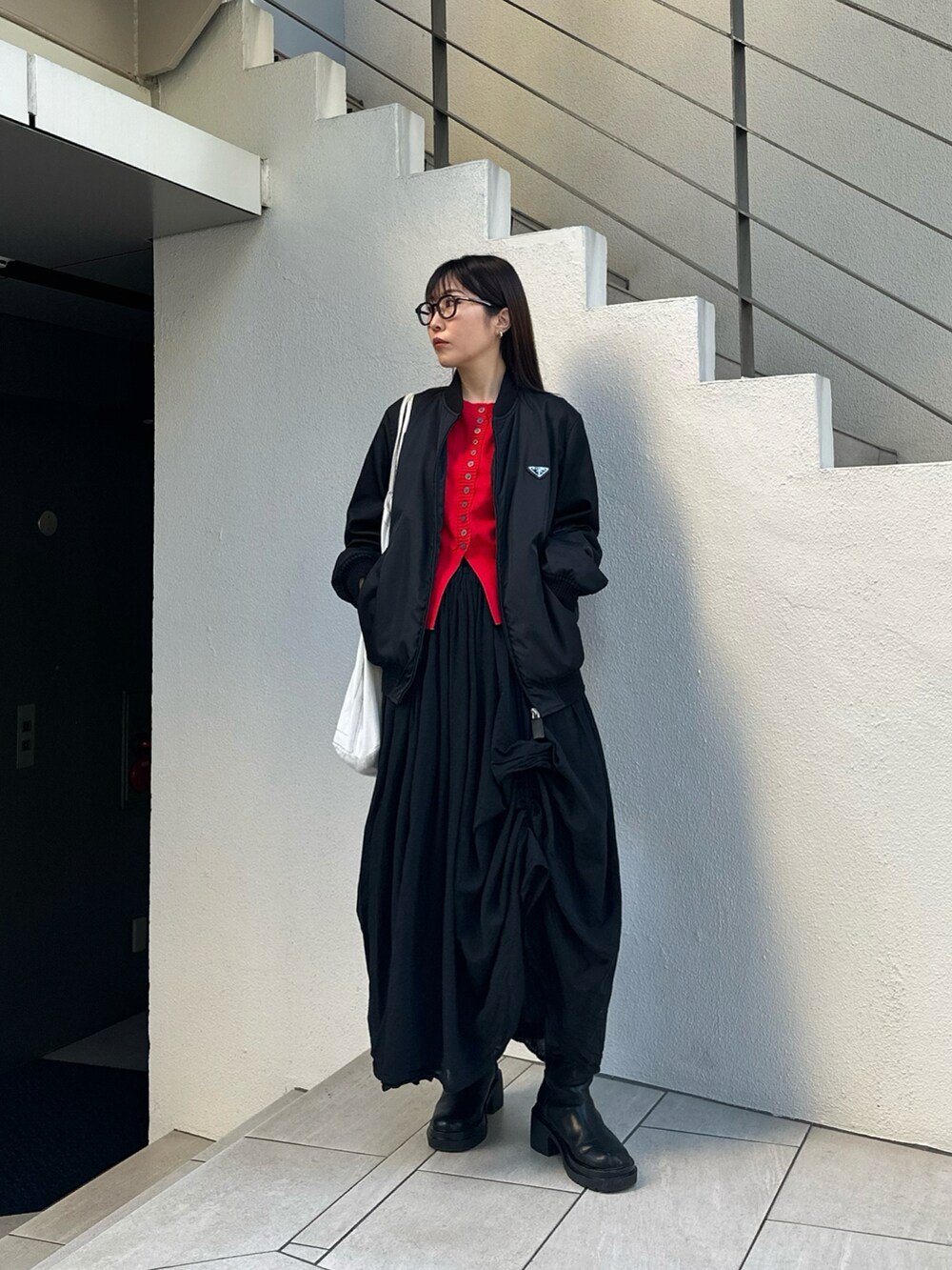 ブラック系のスカート、ブラック系のブーツ、レッド系のカーディガン/ボレロを着用したレディースの冬コーディネートの2枚目の写真