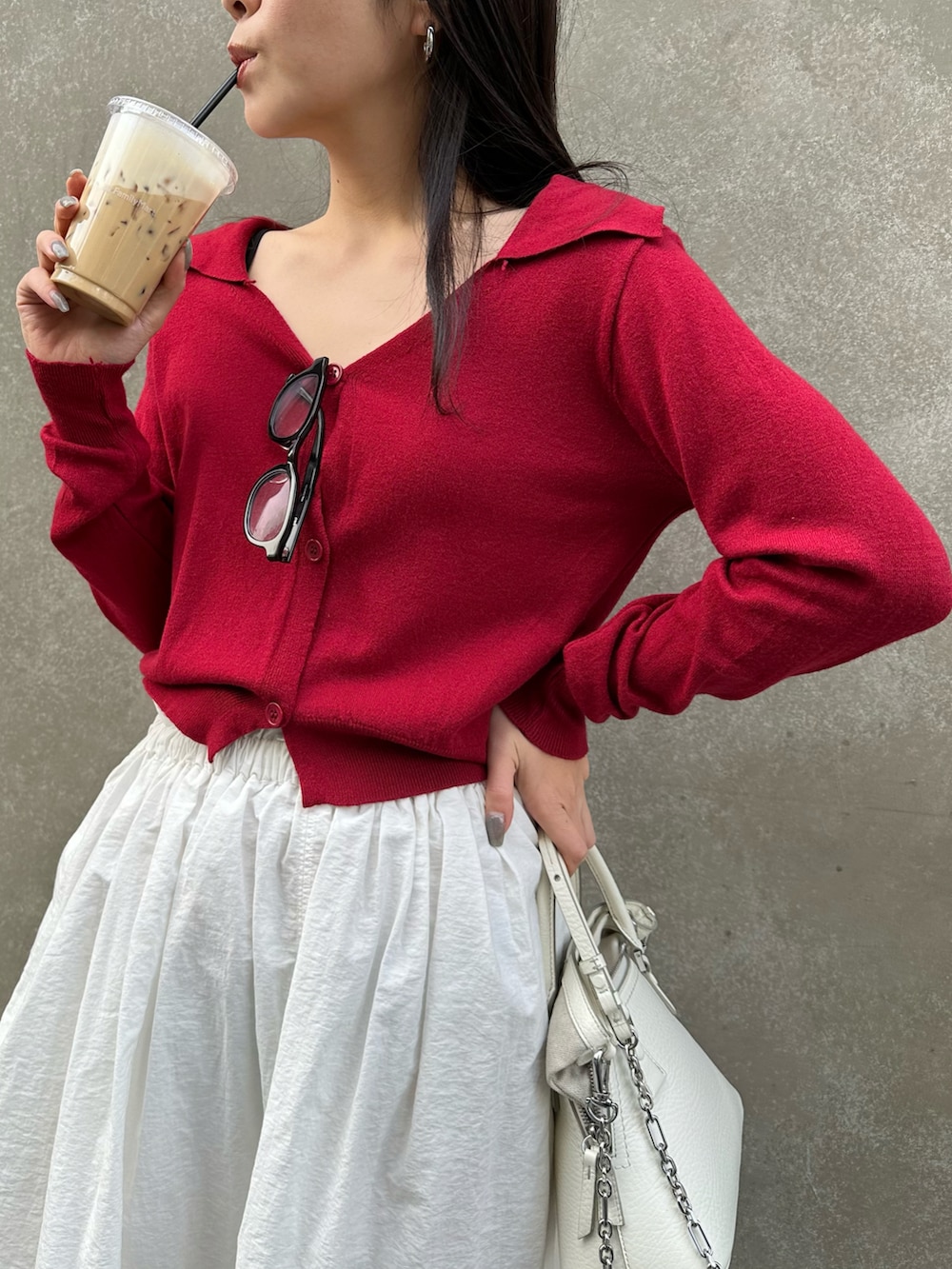 ホワイト系のショルダーバッグ、ホワイト系のスカート、レッド系のカーディガン/ボレロを着用したレディースの冬コーディネートの2枚目の写真