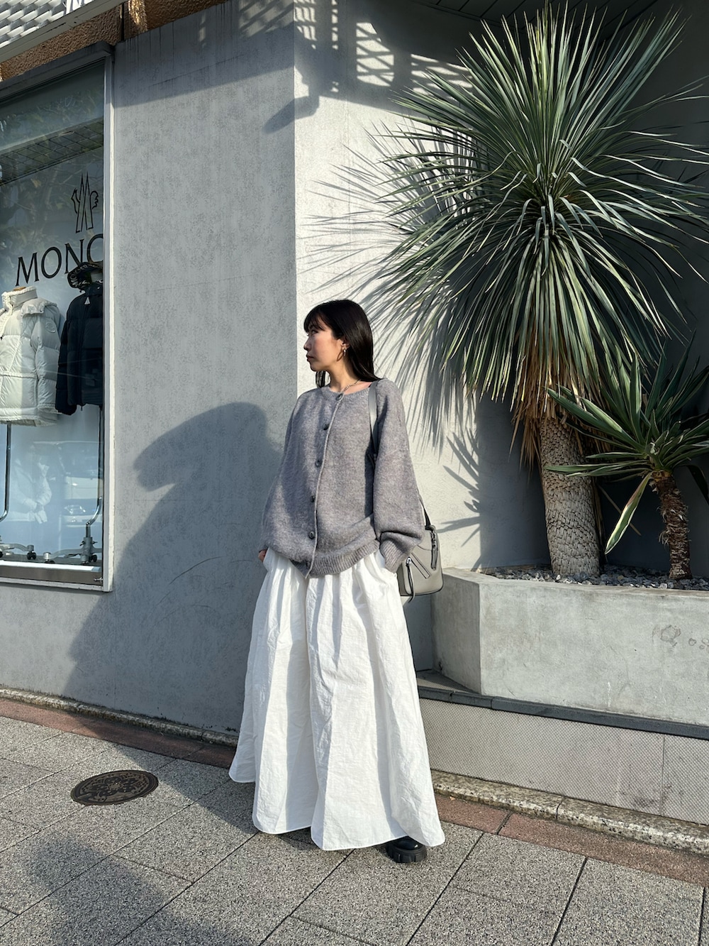 ホワイト系のスカート、グレー系のカーディガン/ボレロ、グレー系のトートバッグを着用したレディースの冬コーディネートの3枚目の写真