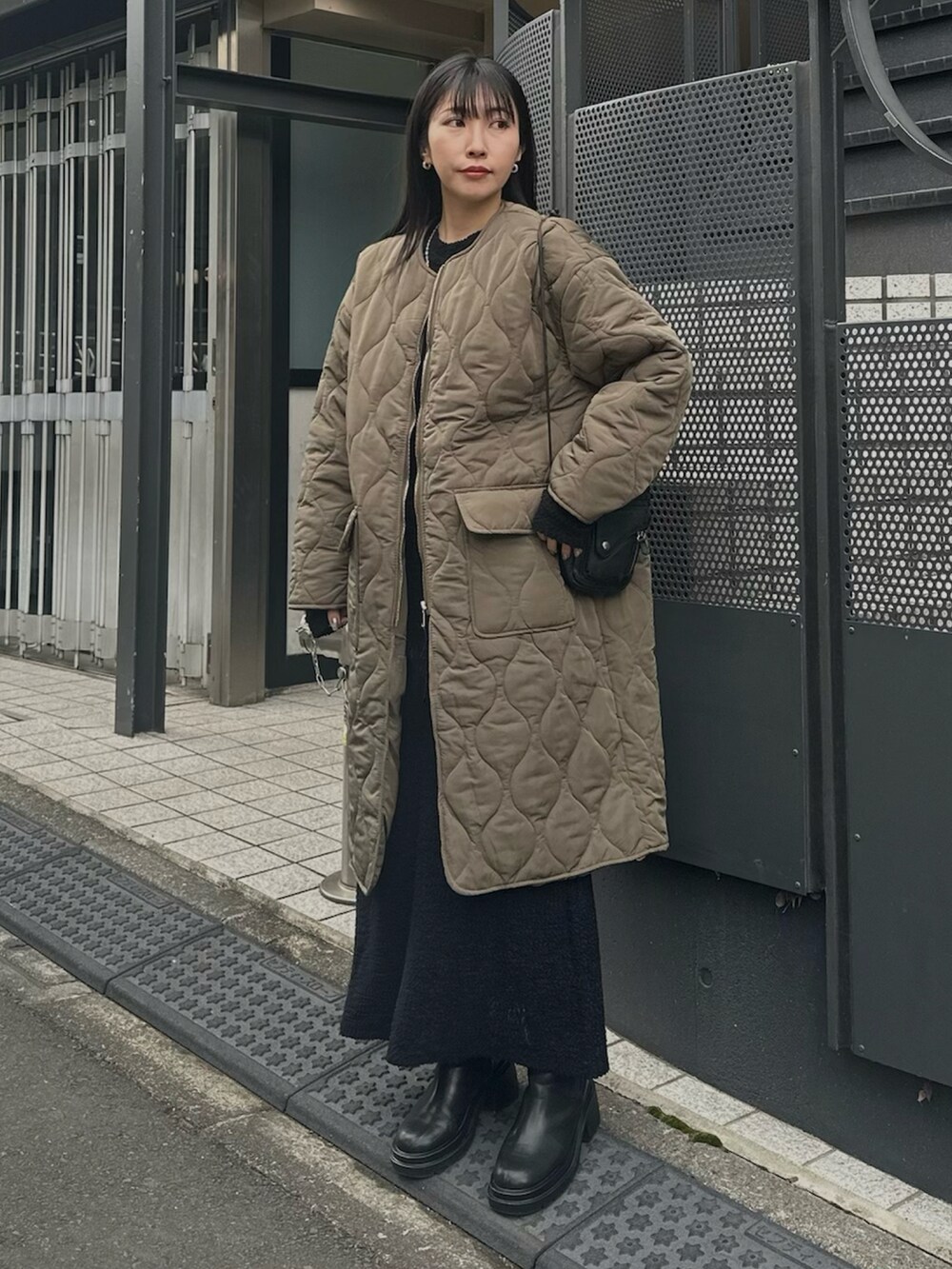 グリーン系のダウンジャケット/コート、ブラック系のワンピース、ブラック系のブーツを着用したレディースの冬コーディネートの2枚目の写真
