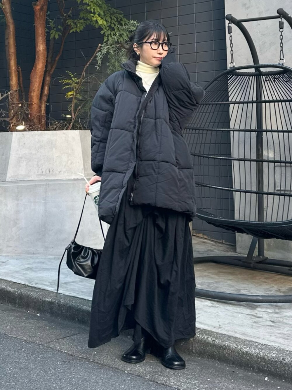 ブラック系のスカート、ブラック系のダウンジャケット/コート、ホワイト系のニット/セーターを着用したレディースの秋コーディネートの2枚目の写真