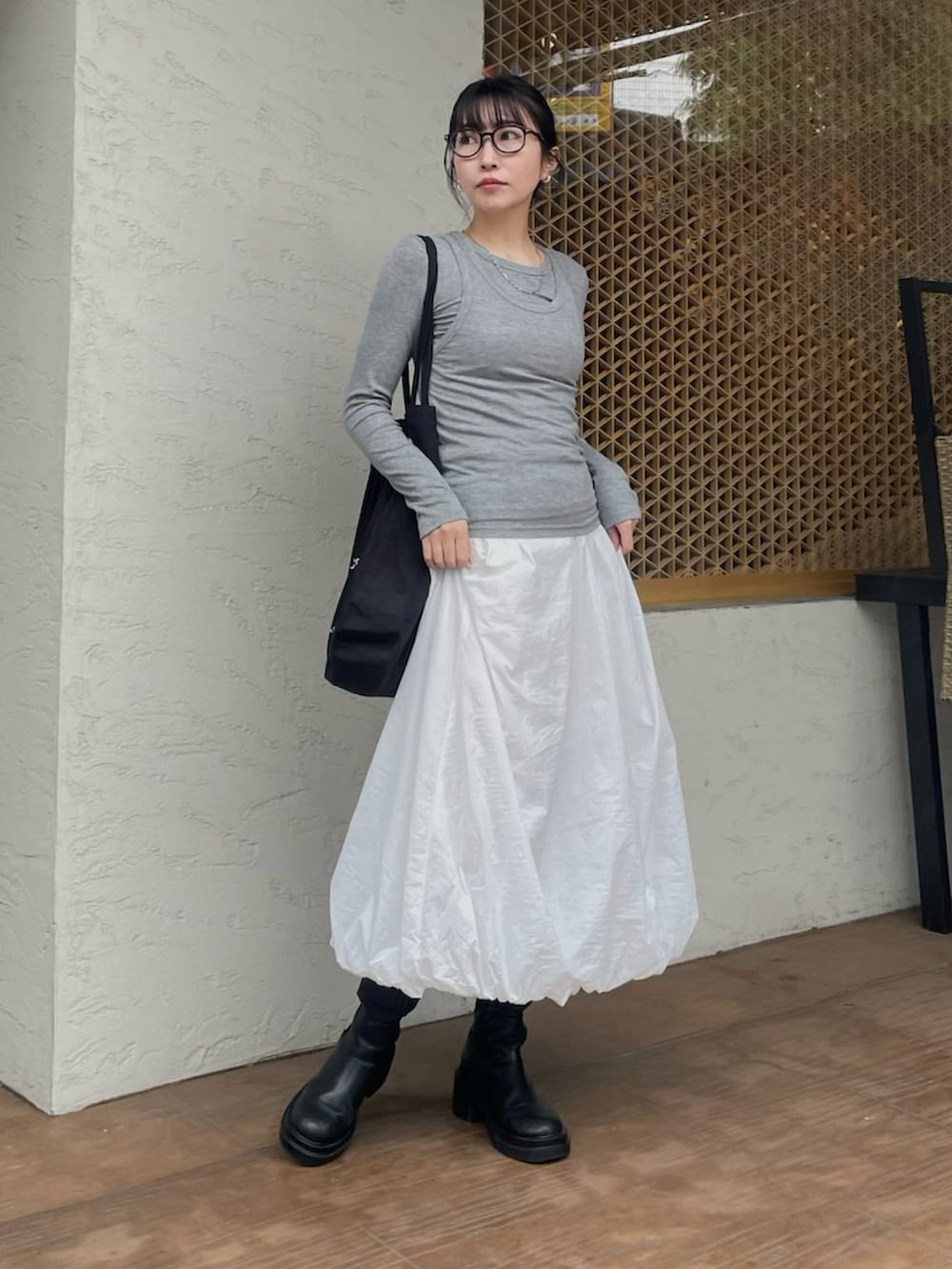 ブラック系のブーツ、グレー系のTシャツ/カットソー、ホワイト系のスカートを着用したレディースの春コーディネートの2枚目の写真