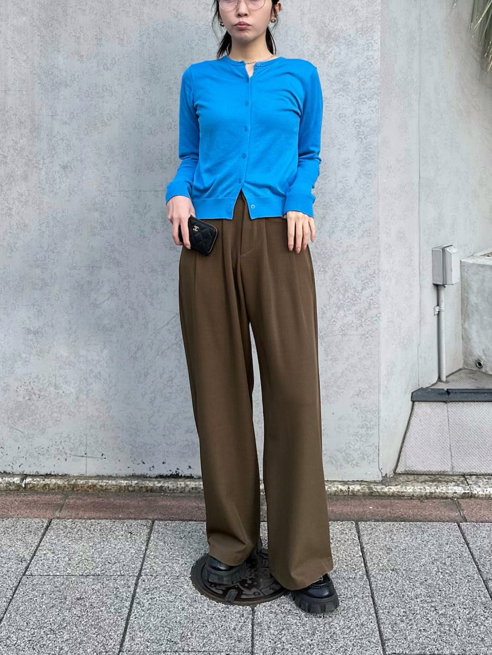 ブラウン系のスラックス、ブラック系のローファー、ブルー系のカーディガン/ボレロを着用したレディースの春コーディネートの2枚目の写真